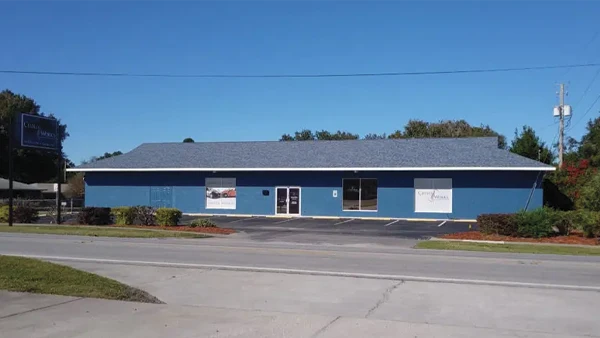 Blue commercial building with white trim, and signage on the facade